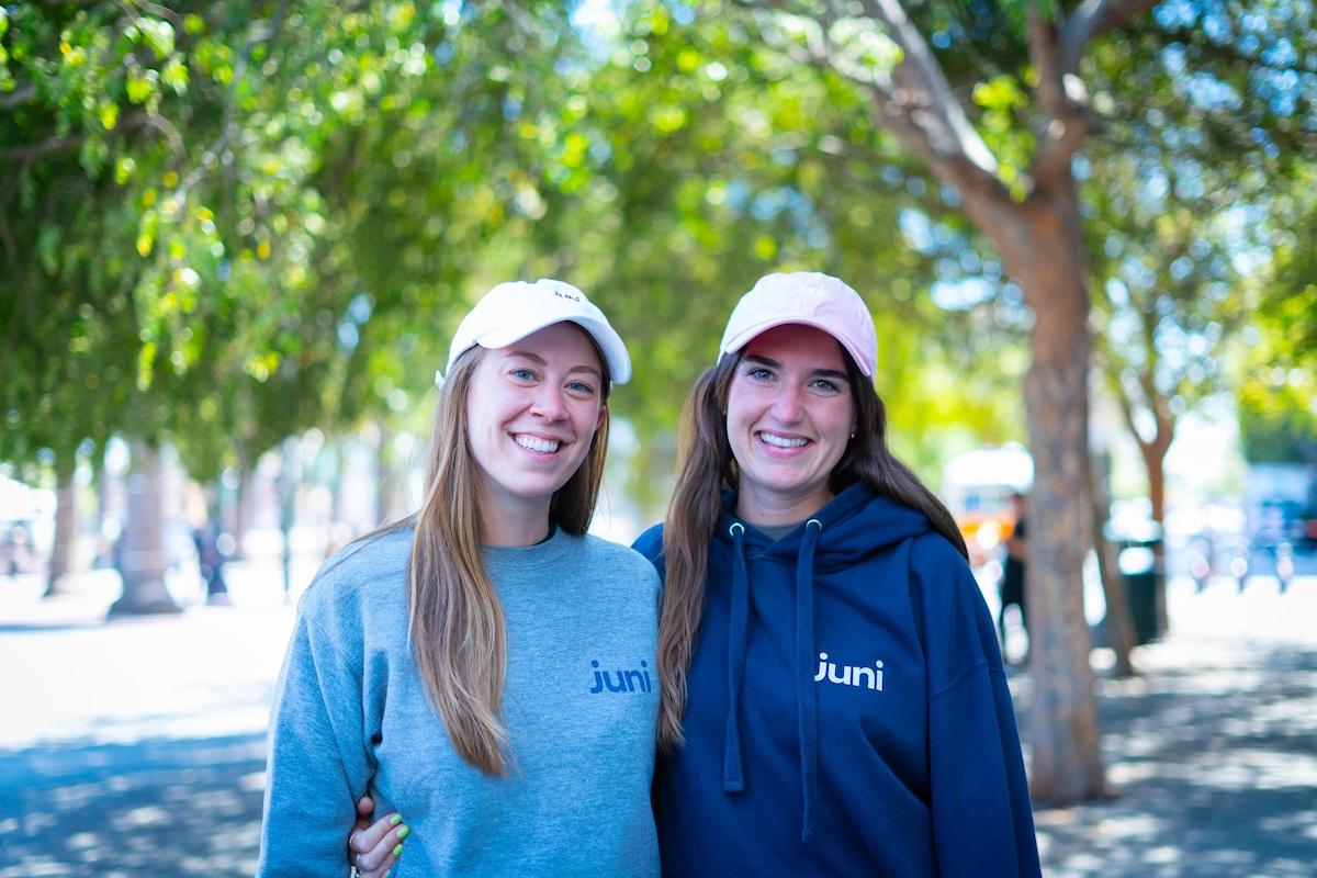 Two women wearing Juni sweater smiling to the camera.